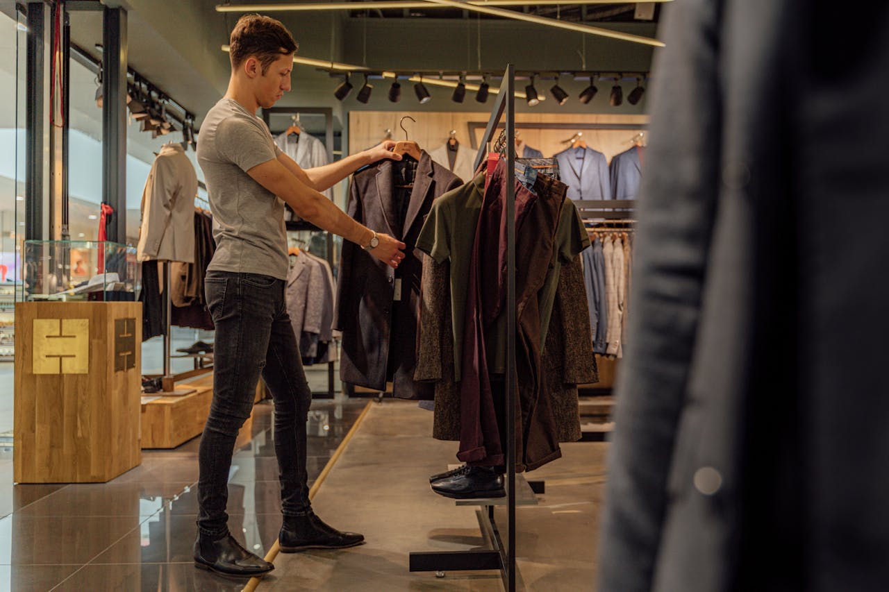 A man browsing stylish blazers in a modern clothing store, focusing on men's fashion.